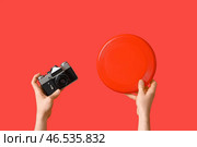 Мужские руки с камерой и фрисби на красном фоне. Стоковое фото, фотограф Pixel_shot / Фотобанк Лори