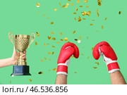 Женская рука с золотым кубком, мужские руки в боксерских перчатках и конфетти на зеленом фоне. Стоковое фото, фотограф Pixel_shot / Фотобанк Лори