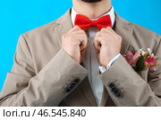 Молодой парень в выпускном костюме поправляет бабочку на синем фоне, крупным планом. Стоковое фото, фотограф Pixel_shot / Фотобанк Лори
