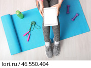Спортивная женщина с планшетным компьютером сидит на мате в спортзале, вид сверху. Стоковое фото, фотограф Pixel_shot / Фотобанк Лори