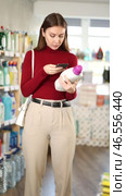 Young woman scanning barcode on mobile large bottle with detergent in household store. Стоковое видео, видеограф Яков Филимонов / Фотобанк Лори