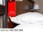 A hotel room with a red sign that says "Please do not disturb." The concept of a hotel stay. Стоковое фото, фотограф Photojuli / Фотобанк Лори