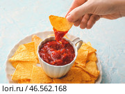 Женщина макает начос во вкусный соус сальса. Стоковое фото, фотограф Pixel_shot / Фотобанк Лори
