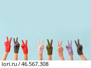 Женщины в теплых перчатках показывают победный жест на синем фоне. Стоковое фото, фотограф Pixel_shot / Фотобанк Лори