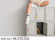 Студентка сидит на шкафчике на светлом фоне. Стоковое фото, фотограф Pixel_shot / Фотобанк Лори