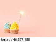 Вкусные день рождения кексы с бенгальской зажигалкой на розовом фоне. Стоковое фото, фотограф Pixel_shot / Фотобанк Лори