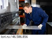 Craftsman positioning metal workpiece on bending machine in workshop. Стоковое фото, фотограф Яков Филимонов / Фотобанк Лори