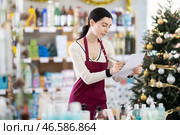 Young woman restocking using paper in store with New Year decoration. Стоковое фото, фотограф Яков Филимонов / Фотобанк Лори