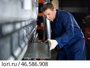 Craftsman positioning metal workpiece on bending machine in workshop. Стоковое фото, фотограф Яков Филимонов / Фотобанк Лори