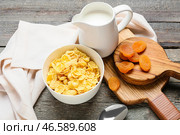 Чаша с вкусными кукурузными хлопьями, кувшин молока и курага на деревянном фоне. Стоковое фото, фотограф Pixel_shot / Фотобанк Лори