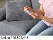Диабетическая молодая женщина использует глюкометр на диване дома. Стоковое фото, фотограф Pixel_shot / Фотобанк Лори