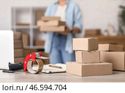 Посылочные коробки с диспенсером упаковочной ленты на столе в складе, крупный план. Стоковое фото, фотограф Pixel_shot / Фотобанк Лори