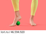 Спортивная молодая женщина массирует свою стопу с помощью мяча на красном фоне, крупный план. Стоковое фото, фотограф Pixel_shot / Фотобанк Лори