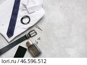 Набор мужских аксессуаров с белой рубашкой, парфюмом и ремнем на белом фоне с потертостями. Вид сверху. Стоковое фото, фотограф Pixel_shot / Фотобанк Лори