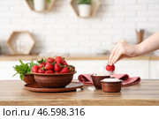 Женщина макает вкусную клубнику в сахар на кухонном столе. Стоковое фото, фотограф Pixel_shot / Фотобанк Лори