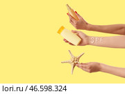 Женские руки с нанесенными буквами SPF, солнцезащитными кремами и морской звездой на желтом фоне. Стоковое фото, фотограф Pixel_shot / Фотобанк Лори