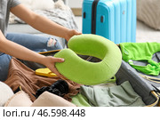 Молодая женщина упаковывает подушку в чемодан на диване дома, крупный план. Концепция летнего путешествия. Стоковое фото, фотограф Pixel_shot / Фотобанк Лори