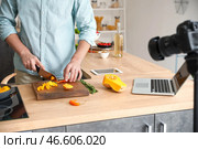 Молодой человек режет тыкву во время записи видеоурока на кухне. Стоковое фото, фотограф Pixel_shot / Фотобанк Лори