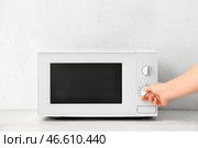 Женщина разогревает еду в микроволновой печи на светлом фоне, крупным планом. Стоковое фото, фотограф Pixel_shot / Фотобанк Лори