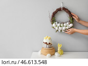 Женщина вешает пасхальный венок на серую стену. Стоковое фото, фотограф Pixel_shot / Фотобанк Лори