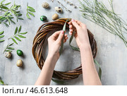 Женщина плетет пасхальный венок на сером фоне. Стоковое фото, фотограф Pixel_shot / Фотобанк Лори