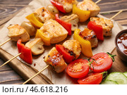 Деревянная доска с куриными шашлычками на гриле с овощами на столе, крупным планом. Стоковое фото, фотограф Pixel_shot / Фотобанк Лори