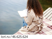 Молодая афроамериканка читает книгу с пустыми страницами у реки. Стоковое фото, фотограф Pixel_shot / Фотобанк Лори