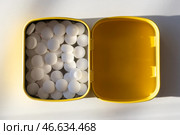 Открытая желтая жестяная коробочка с белыми мятными леденцами на белом фоне. Стоковое фото, фотограф Anton Leonchikov / Фотобанк Лори
