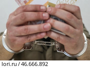 Наручники на арестованном преступнике и деньги. Стоковое фото, фотограф Сергей Булкин/NEWS.ru / ТАСС / Фотобанк Лори