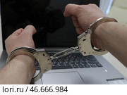 Наручники на руках преступника, занимавшегося мошенничеством в сети Интернет, и ноутбук. Стоковое фото, фотограф Сергей Булкин/NEWS.ru / ТАСС / Фотобанк Лори