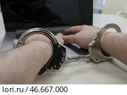 Наручники на руках преступника, занимавшегося мошенничеством в сети Интернет, и ноутбук. Стоковое фото, фотограф Сергей Булкин/NEWS.ru / ТАСС / Фотобанк Лори