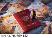 Заграничный паспорт гражданина Российской Федерации, брелок в форме матрешки на фоне банкнот номиналом 5000 российских рублей. Стоковое фото, фотограф Александр Манзюк / ТАСС / Фотобанк Лори