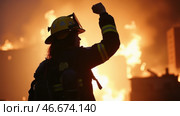 Firefighter is standing in front of a burning building. Стоковое AI-изображение, AI-художник Sergey Grishin / Фотобанк Лори
