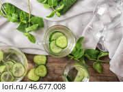 Стеклянная чашка вкусной свежей огуречной воды на деревянном столе. Стоковое фото, фотограф Pixel_shot / Фотобанк Лори