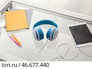 Наушники с планшетным ПК и канцелярские принадлежности на стеклянном столе. Стоковое фото, фотограф Pixel_shot / Фотобанк Лори