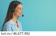 Customer service operator with telephone headset on his head. Young smiling woman receives call on direct line for customers. Portrait of support employee, blue background, copy space for text. Стоковое AI-видео, аниматор Ирина / Фотобанк Лори