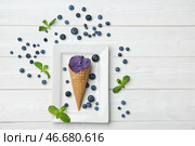 Вафельный рожок с вкусным мороженым и черникой на белом фоне деревянные. Стоковое фото, фотограф Pixel_shot / Фотобанк Лори