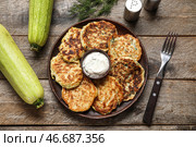 Тарелка вкусных кабачковых оладий с сметаной на деревянном фоне. Стоковое фото, фотограф Pixel_shot / Фотобанк Лори