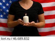 Женщина держит горящую свечу на фоне флага США. Национальный день молитвы и воспоминания о жертвах террористических атак. Стоковое фото, фотограф Pixel_shot / Фотобанк Лори