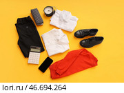 Сочинение с модной школьной формой, будильником, мобильным телефоном и канцелярскими принадлежностями на оранжевом фоне. Стоковое фото, фотограф Pixel_shot / Фотобанк Лори