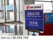 Табличка компании Air China с надписями экономический класс и премиум экономический класс. Ухань, Китай (2024 год). Редакционное фото, фотограф Кекяляйнен Андрей / Фотобанк Лори