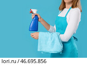Молодая женщина с бутылкой моющего средства и тряпкой на голубом фоне, крупным планом. Стоковое фото, фотограф Pixel_shot / Фотобанк Лори