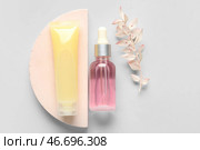 Состав с косметическими продуктами, гипсовым постаментом и высохшим растением на светлом фоне. Стоковое фото, фотограф Pixel_shot / Фотобанк Лори