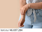 Аллергичная молодая женщина чешет себя на бежевом фоне, крупным планом. Стоковое фото, фотограф Pixel_shot / Фотобанк Лори