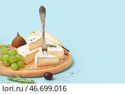 Деревянная доска с кусочками вкусного сыра Камамбер на голубом фоне. Стоковое фото, фотограф Pixel_shot / Фотобанк Лори