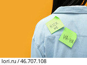Липкие бумаги на спине женщины на оранжевом фоне, крупным планом. Празднование Дня смеха. Стоковое фото, фотограф Pixel_shot / Фотобанк Лори