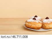 Тарелка с вкусными пончиками для празднования Хануки на деревянном столе на фоне цветного фона. Стоковое фото, фотограф Pixel_shot / Фотобанк Лори