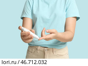Молодая женщина с диабетом использует ланцетную ручку на синем фоне, крупный план. Стоковое фото, фотограф Pixel_shot / Фотобанк Лори