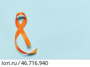 Оранжевая лента на синем фоне. Месяц осведомленности о рассеянном склерозе. Стоковое фото, фотограф Pixel_shot / Фотобанк Лори