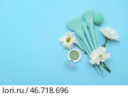 Красивый натюрморт с цветами, кистями для макияжа и моно-палеткой теней на синем фоне. Стоковое фото, фотограф Pixel_shot / Фотобанк Лори